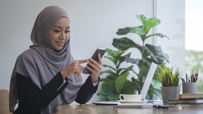 ilustrasi-wanita-hijab-pakai-ponsel-dan-laptop